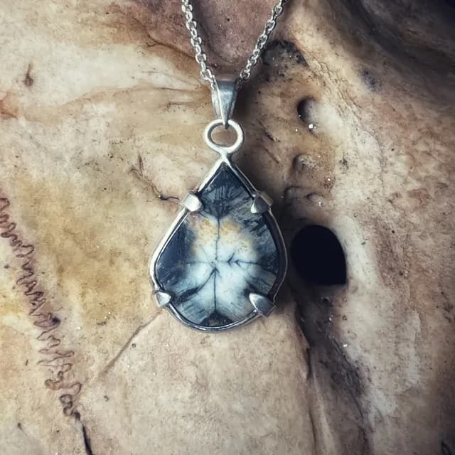 Gros plan sur le pendentif en goutte avec pierre andalousite sertie sur une monture en argent.